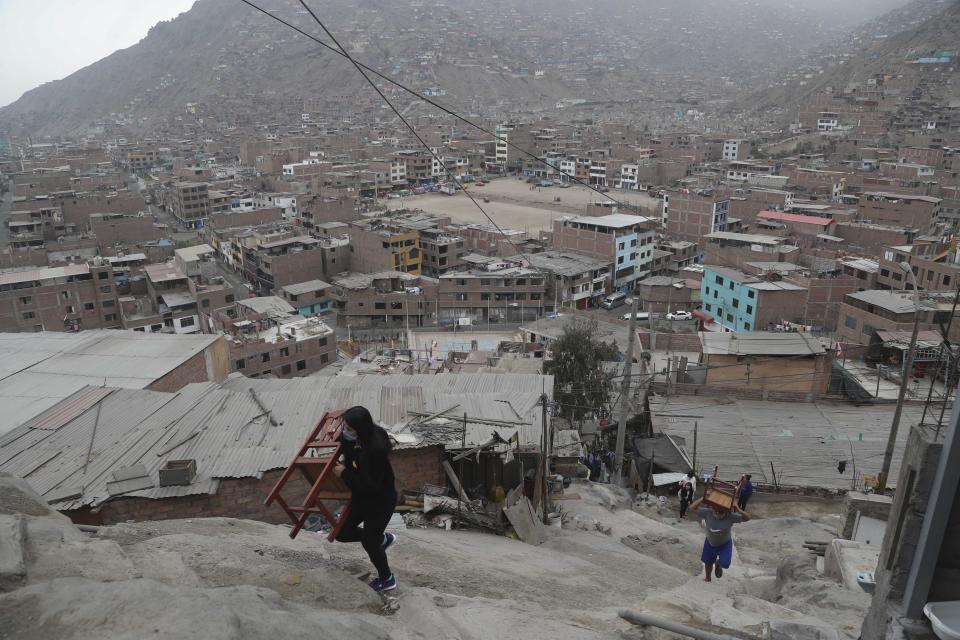 Residents, equipped with their chairs, ascend a flight of stairs to the top of a hill where barber Josue Yacahuanca is offering free haircuts, in the San Juan de Lurigancho neighborhood of Lima, Peru, Friday, June 19, 2020. Yacahuanca seeks out clients devastated by a quarantine that's gone on for nearly 100 days in an attempt to stem the wave of new coronavirus infections. (AP Photo/Martin Mejia)
