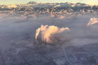 In this photo taken Wednesday Dec. 5, 2018 from a plane, smoke stacks are seen near the city of Urumqi China's northwestern region of Xinjiang. (AP Photo/Ng Han Guan)