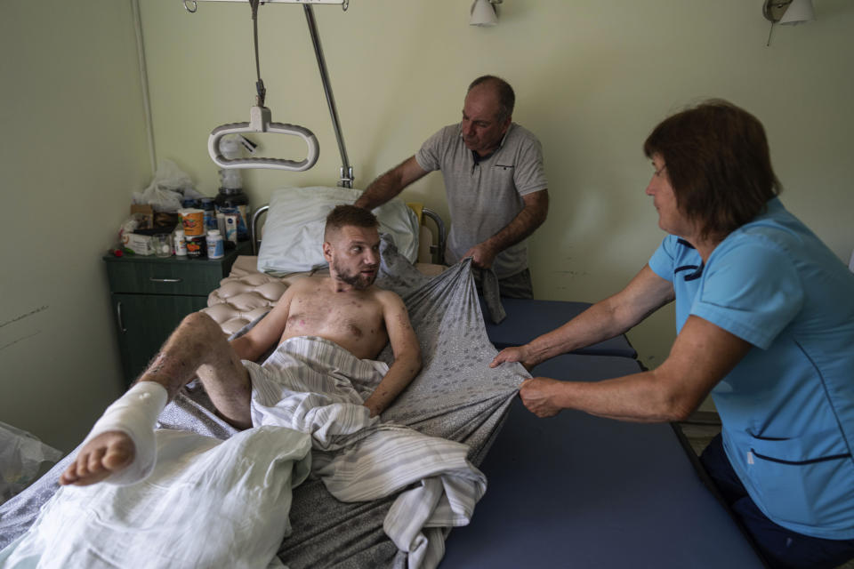 Medics transfer Vitaliy Bilyak to a stretcher at St. Panteleimon hospital in Lviv, Ukraine, Tuesday, July 25, 2023. The Ukrainian soldier's skinny body is a web of scars that end with an amputation above the knee. Ukraine is facing the prospect of a future with upwards of 20,000 amputees, many of them soldiers who are also suffering psychological trauma from their time at the front. (AP Photo/Evgeniy Maloletka)