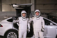 In this Friday, Jan. 17, 2020 photo made available by NASA, astronauts Doug Hurley, left, and Robert Behnken pose in front of a Tesla Model X car during a SpaceX launch dress rehearsal at Kennedy Space Center in Cape Canaveral, Fla. The NASA astronauts rode to the pad in the electric vehicle made by Elon Musk's company. (Kim Shiflett/NASA via AP)