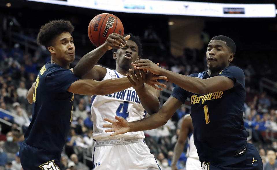 Marquette guard Kam Jones (1) and forward Oso Ighodaro (13) vie for the ball against Seton Hall forward Tyrese Samuel (4) during the second half of an NCAA college basketball game in Newark, N.J., Wednesday, Jan. 26, 2022. Marquette won 73-63. (AP Photo/Noah K. Murray)