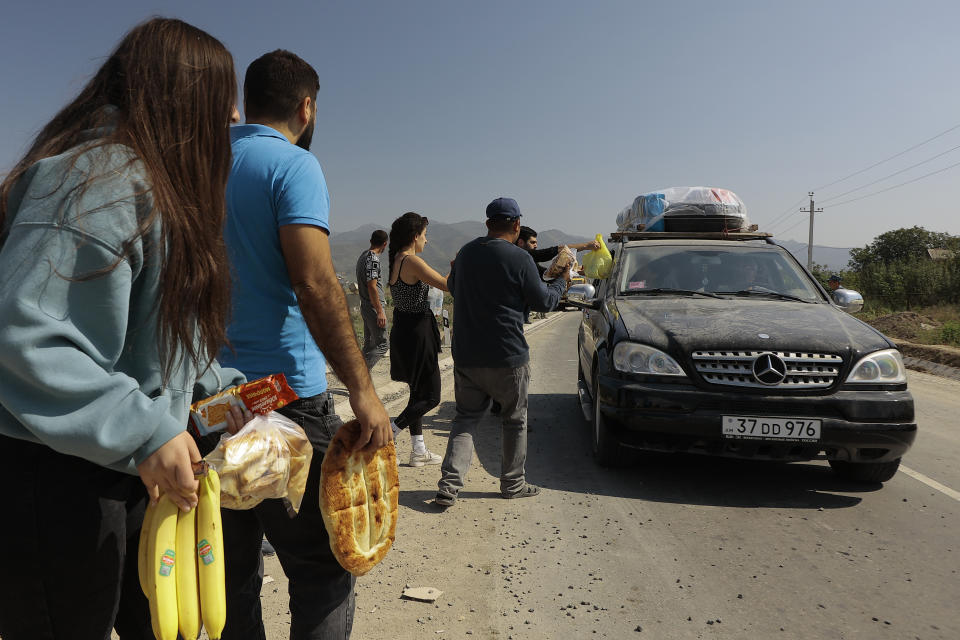 Volunteers offer food to ethnic Armenians from Nagorno-Karabakh, moving on the way from Nagorno-Karabakh to Armenia's Kornidzor in Syunik region, Armenia, Friday, Sept. 29, 2023. More than 70% of Nagorno-Karabakh's original population has fled to Armenia as the region's separatist government said it will dissolve itself and the unrecognized republic inside Azerbaijan will cease to exist by year’s end after a three-decade bid for independence.(AP Photo/Vasily Krestyaninov)