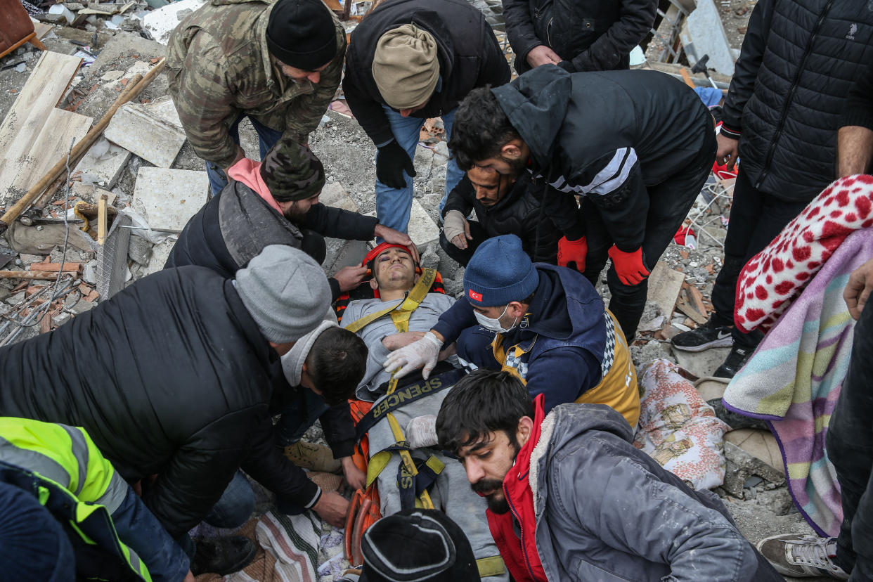 Workers help a man who was rescued from the rubble of a six-story building.