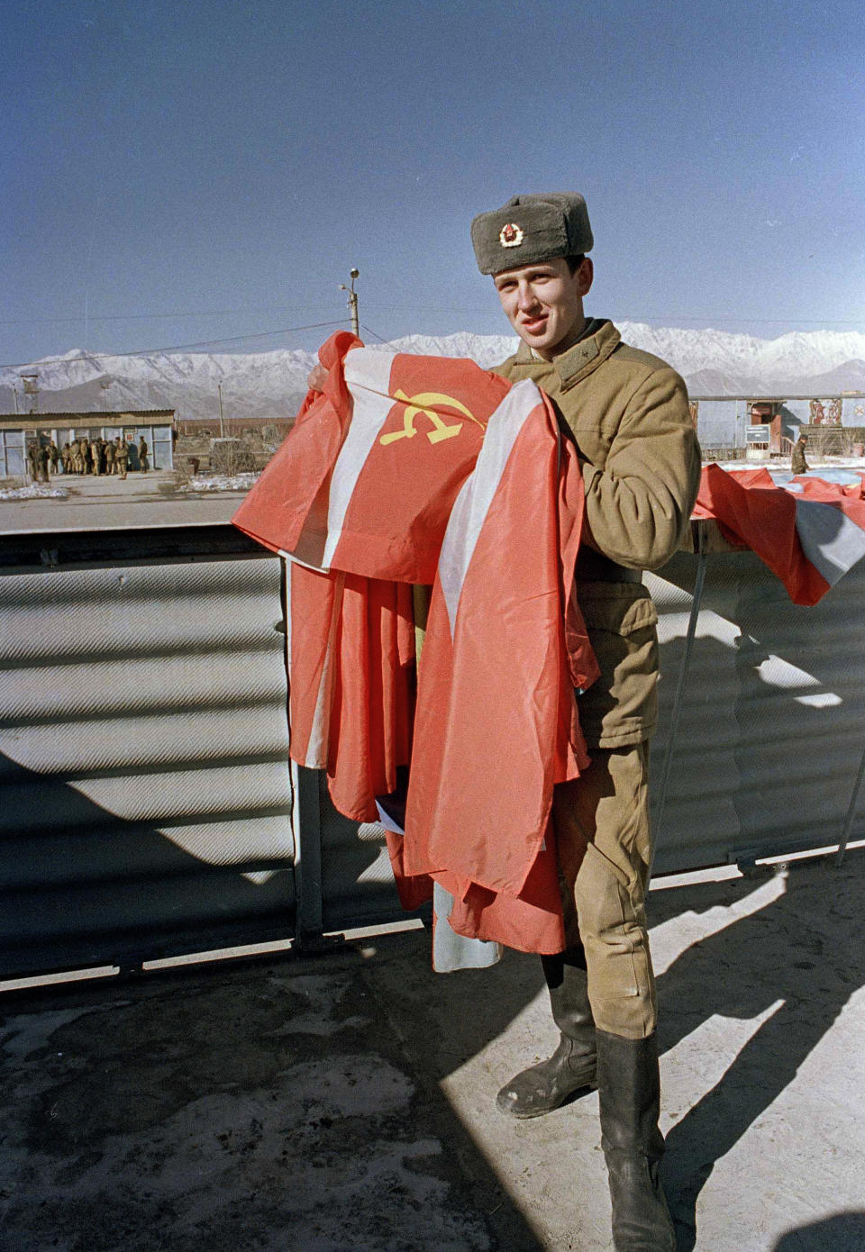 FILE - In this Jan. 25, 1989 file photo, a Soviet soldier folds the Soviet flag at Kabul air base as the Soviet military prepare for their final withdrawal from war-torn Afghanistan. A UN-brokered accord set a Feb. 15 pullout date. Afghanistan is marking the 31st anniversary of the Soviet Union's last soldier leaving the country, Saturday, Feb. 15, 2020. This year's anniversary comes as the United States negotiates its own exit after 18 years of war, America's longest. (AP Photo/Liu Heung Shing)