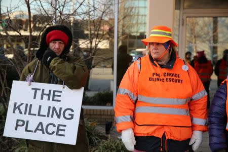 A protester (L) and an escort who ensures women can reach the clinic stand outside the EMW WomenÕs Surgical Center in Louisville, Kentucky, U.S. January 27, 2017. REUTERS/Chris Kenning