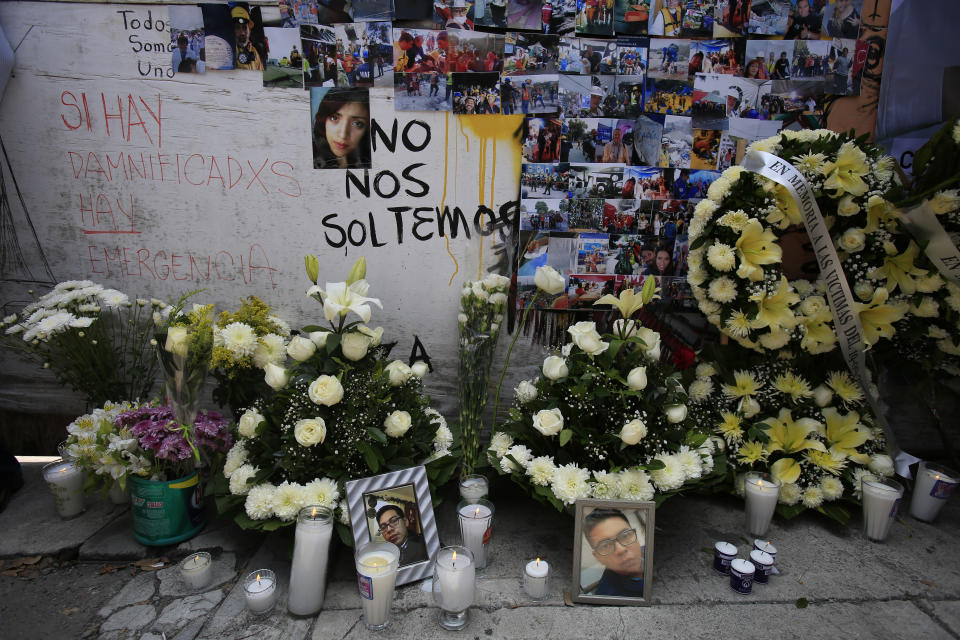 Photographs of victims and the rescue efforts are placed around flowers in front of the site at Alvaro Obregon 286 where 49 died when their office building collapsed in last year's 7.1 magnitude earthquake, in Mexico City, Wednesday, Sept. 19, 2018. Across the city, memorials were held at sites where hundreds perished in the Sept. 19, 2017 quake.(AP Photo/Rebecca Blackwell)