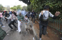 Student protesters run from tear gas fired by riot police during a clash in Jakarta, Indonesia, Monday, Sept. 30, 2019. Thousands of Indonesian students resumed protests on Monday against a new law they say has crippled the country's anti-corruption agency, with some clashing with police.(AP Photo/Achmad Ibrahim)