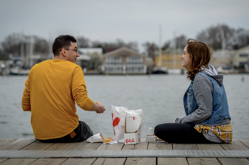 Cameron Shaver and Callie Johnson practice social distancing to prevent the spread of coronavirus disease (COVID-19) as they enjoy dinner at City Dock in Annapolis, U.S., March 18, 2020. (Photo: REUTERS/Mary F. Calvert)