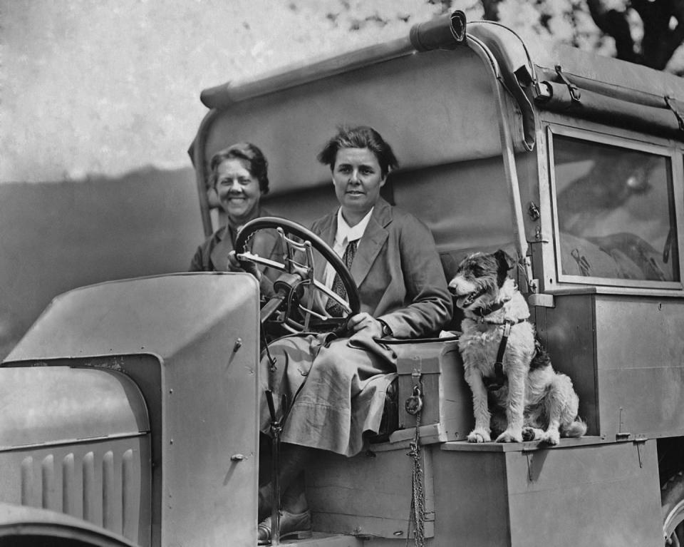 <p>Two women and a smiling pooch sit in the front of a truck.</p>
