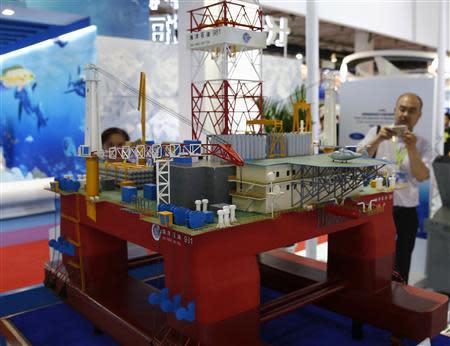 A visitor takes a picture of a scale model of the Chinese oil rig Haiyang Shi You 981 during the China Beijing International High-Tech Expo in Beijing, May 16, 2014. REUTERS/Kim Kyung-Hoon