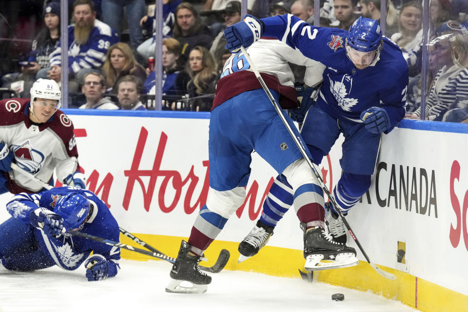 Toronto Maple Leafs defenseman Simon Benoit (2) battles for the puck in the boards with Colorado Avalanche defenseman Kurtis MacDermid (56) during the first period of an NHL hockey game, Saturday, Jan. 13, 2024 in Toronto. (Chris Young/The Canadian Press via AP)