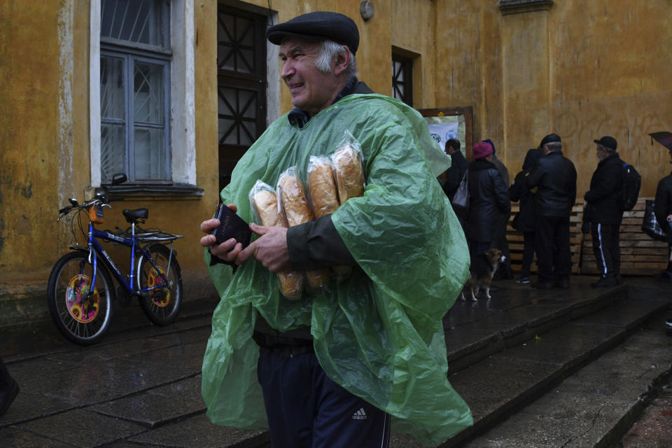 A man carries Ukrainian passport and bread after receiving it at humanitarian aid center in Kramatorsk, Ukraine, Wednesday, Oct. 26, 2022. (AP Photo/Andriy Andriyenko)