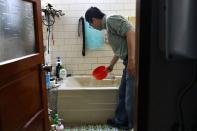 Man scoops water from a bathtub, where he stores water amid water rationing during an island-wide drought, in Hsinchu