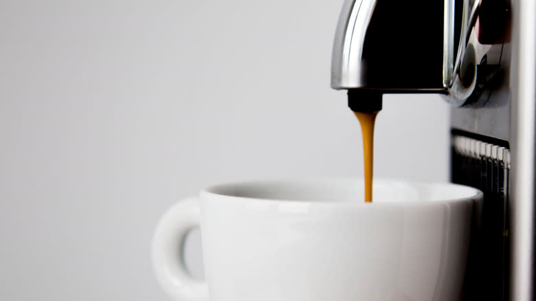 Close-up of the top of a Nespresso machine pouring coffee