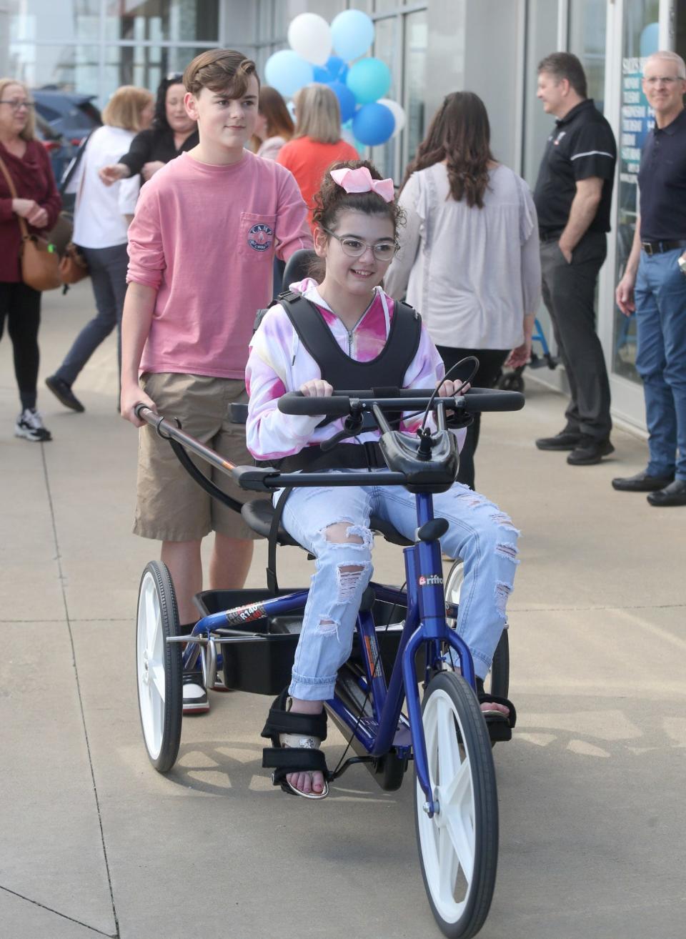Joey McClure, left, helps big sister Miah navigate her new adaptive tricycle, which was presented to the Hoover High School student at Cain Toyota-BMW this week.