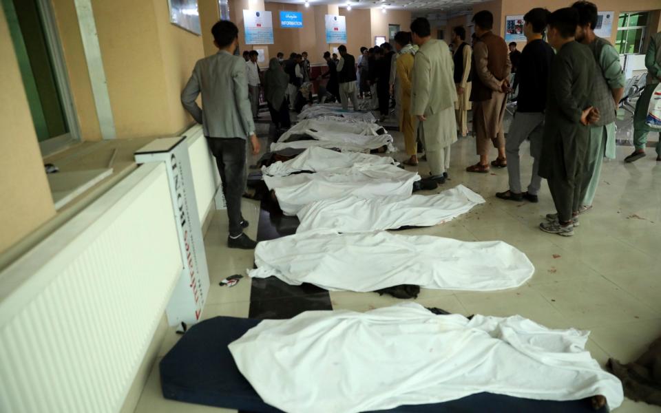 Afghan men try to identify dead bodies at a hospital after an explosion near a school west of Kabul in May - AP