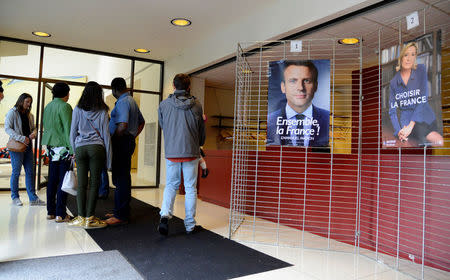 French citizens living in the United States arrive to cast their ballots for the French presidential run-off between Emmanuel Macron (L poster) and Marine Le Pen (R poster), at the French Embassy in Washington, U.S., May 6, 2017. REUTERS/Mike Theiler