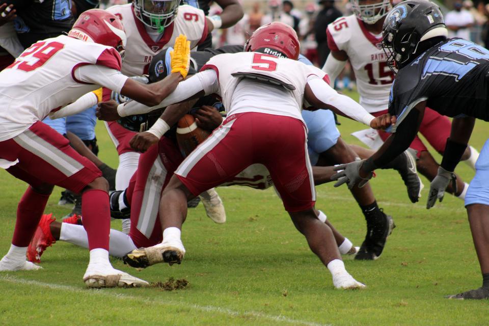Raines defenders Jyon Simon (9), Jaylen Clark (5) and Terrence Forbes (10, underneath ball carrier) combine to force a fumble against Ribault. The Northwest Jacksonville rivals both occupy District 3-3A for 2024 and 2025.