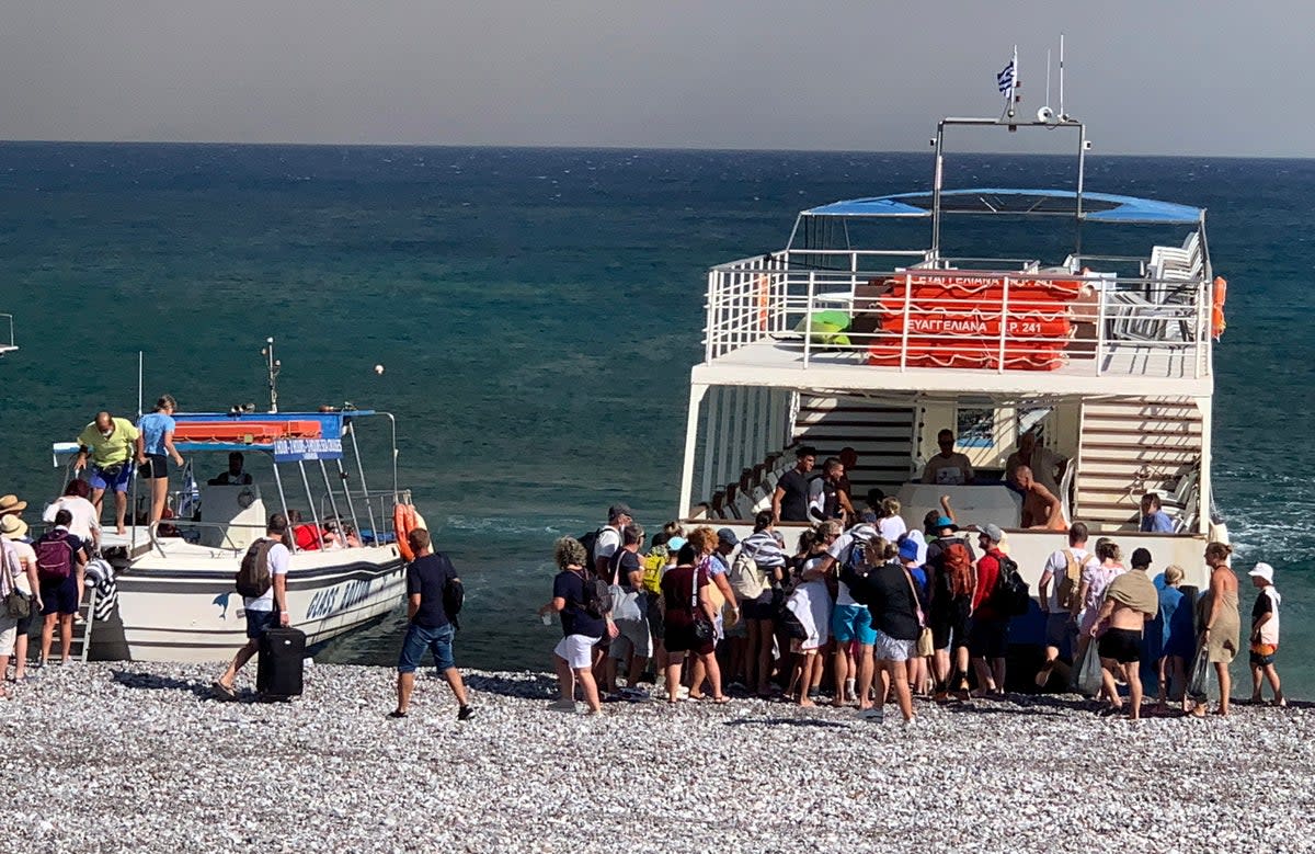 Tourists stand on a beach after being evacuated during a forest fire on the island of Rhodes (EPA)