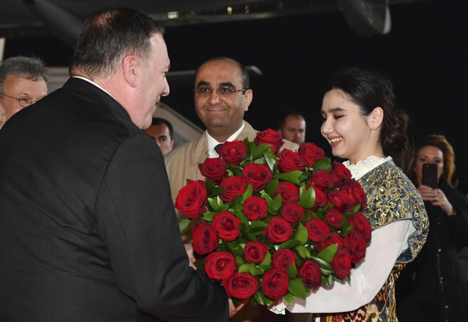 An Uzbek woman presents a bunch of flowers to U.S. Secretary of State Mike Pompeo, left, upon his arrival at the International airport outside Tashkent, Uzbekistan, Sunday, Feb. 2, 2020. (AP Photo)