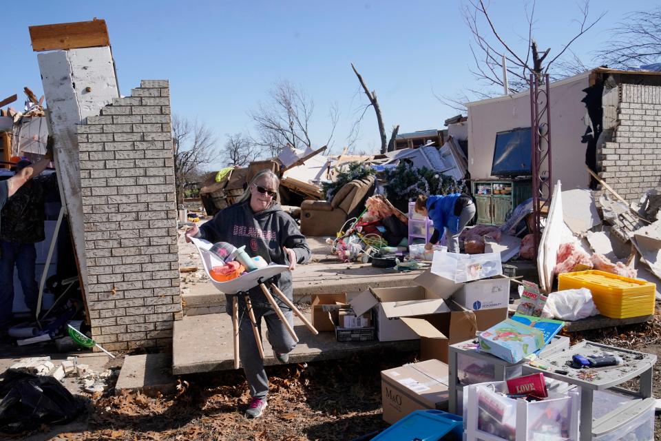 Belinda Penner carries belonging from her cousin’s home, destroyed by a tornado, Tuesday, Dec. 13, 2022, in Wayne, Oklahoma (AP)