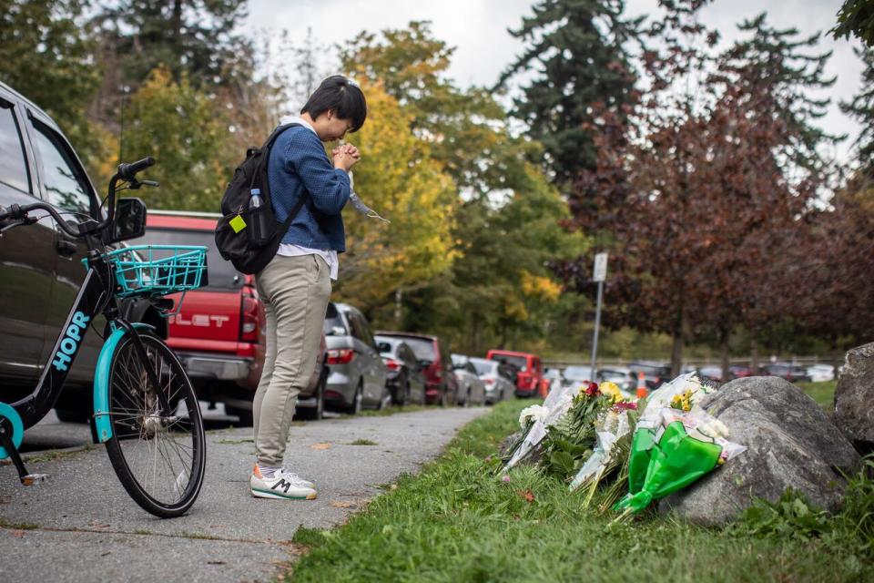 A person leaves flowers at a memorial to two UBC students who were struck and killed by a driver on Northwest Marine Drive at the University of British Columbia in Vancouver, British Columbia on Monday, September 27, 2021.