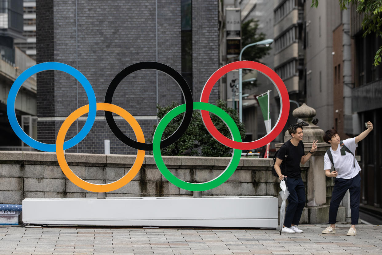 Two men take a selfie in front of the Olympic Rings in Tokyo, Japan.