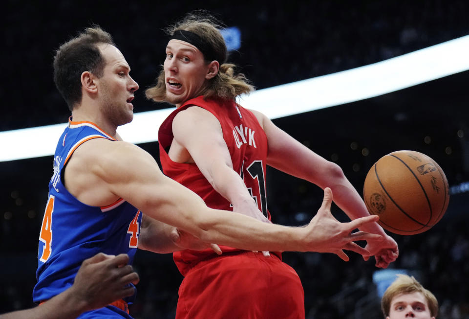 New York Knicks forward Bojan Bogdanovic, left, passes the ball around Toronto Raptors forward Kelly Olynyk during the second half of an NBA basketball game Wednesday, March 27, 2024, in Toronto. (Frank Gunn/The Canadian Press via AP)