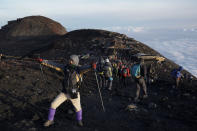 A climber poses for photos after watching the sunrise on the summit of Mount Fuji in Japan, Tuesday, Aug. 27, 2019. (AP Photo/Jae C. Hong)