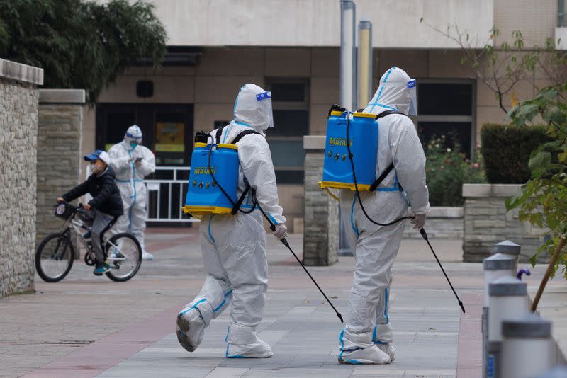 Pandemic prevention workers in protective suits spray disinfectant in a residential compound that was placed under lockdown as outbreaks of coronavirus disease (COVID-19) continue in Beijing