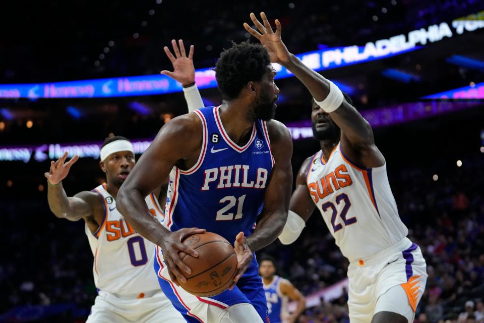 Philadelphia 76ers' Joel Embiid, tries to get the ball past Phoenix Suns' Torrey Craig, left, and Deandre Ayton during the first half of an NBA basketball game, Monday, Nov. 7, 2022, in Philadelphia. (AP Photo/Matt Slocum)