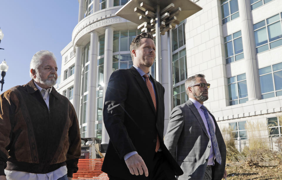 Paul Petersen, center, an Arizona elected official accused of running a multi-state adoption scheme, leaves court following an initial appearance on charges filed in the state Friday, Nov. 15, 2019, in Salt Lake City. Prosecutors in three states say Petersen brought pregnant women from the Marshall Islands to the United States and paid them to give up their babies for adoption. He's pleaded not guilty. (AP Photo/Rick Bowmer)