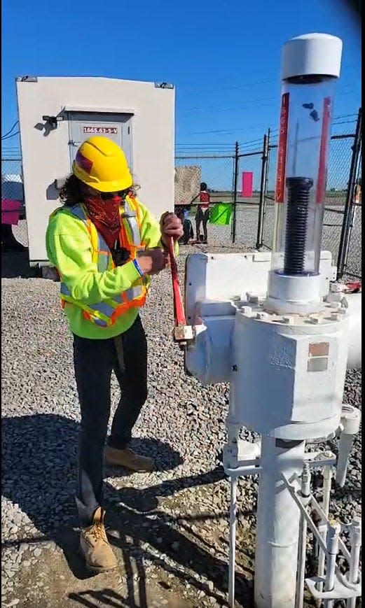 A masked, helmeted protestor, trespassing at an Enbridge pumping station near Vassar in Tuscola County, turns a wrench to close an emergency shutoff valve to Line 5, the controversial oil and gas pipelines that operate through Michigan, including underwater in the Straits of Mackinac, during a demonstration protesting the pipeline's continued operation on October 19, 2021.