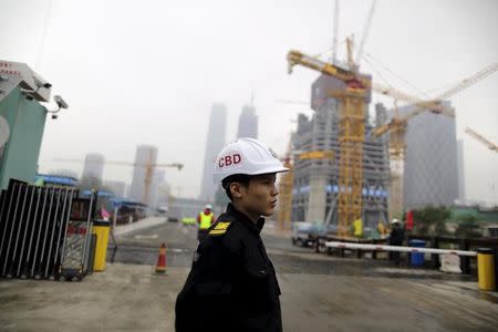 A security personnel stands at the entrance to a construction site of a business building at the Central Business District (CBD) area, in Beijing, China, October 26, 2015. REUTERS/Jason Lee/Files