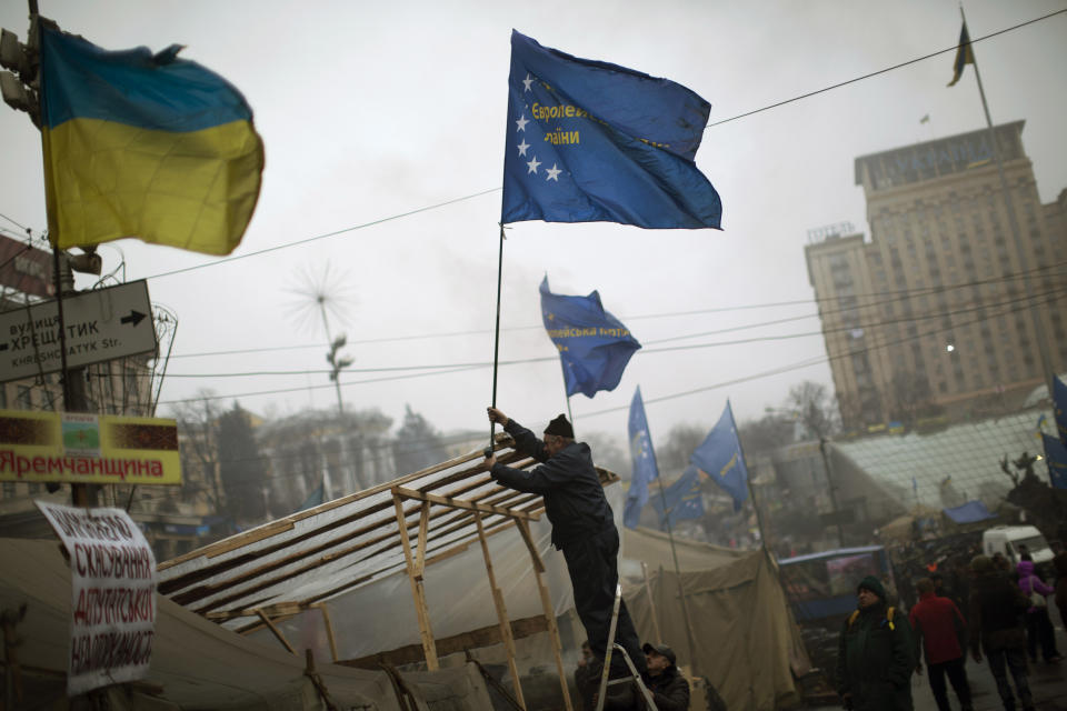 An anti-Yanukovych protester sets an European Union flag on top of a tent in Kiev's Independence Square, the epicenter of the country's current unrest, Ukraine, Sunday, March 2, 2014. A convoy of hundreds of Russian troops is heading toward the regional capital, Simferopol on the Crimean peninsula in Ukraine today. On the road from Sevastopol, the Crimean port where Russia maintains a naval base, AP journalists saw 12 military trucks. Russian troops took over the strategic Black Sea peninsula yesterday and are ignoring international protests. (AP Photo/Emilio Morenatti)