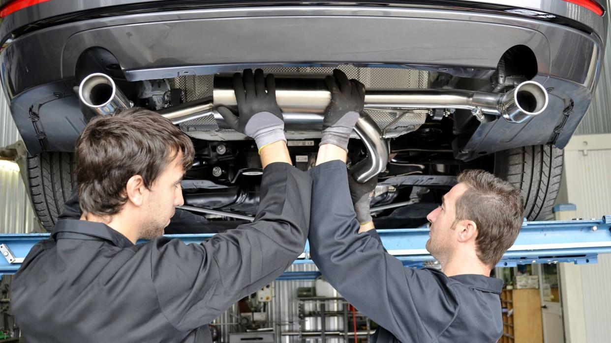 mechanics installing custom muffler