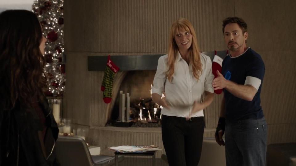 Tony and Pepper in front of a fireplace with Christmas stockings