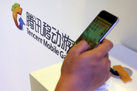 FILE PHOTO: A visitor plays a game on a smartphone at Tencent's exhibition booth at the Global Mobile Internet Conference (GMIC) 2015 in Beijing, China, April 28, 2015. REUTERS/Kim Kyung-Hoon/File Photo