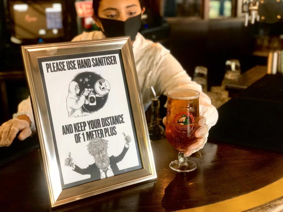 Serving pints behind a social distancing sign at Home Bar & Kitchen, west London