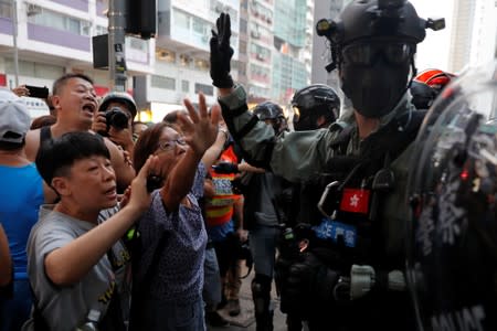 People argue with riot police during a protest against the invocation of the emergency laws in Hong Kong