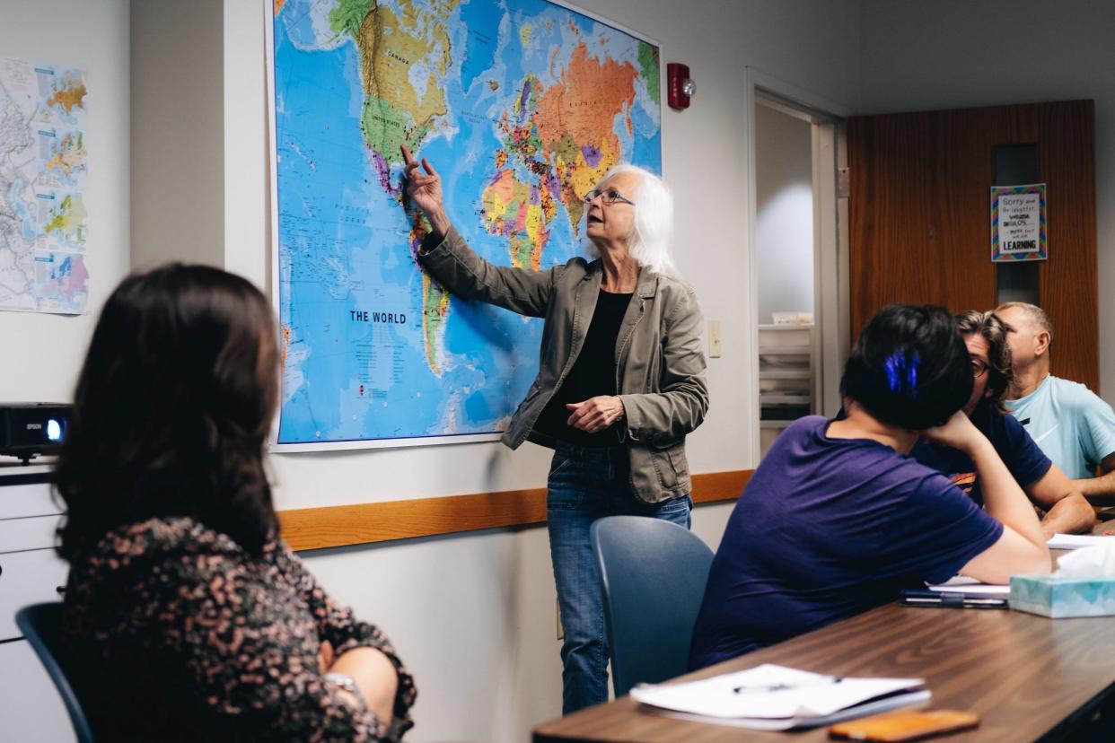 Teaching volunteer, Jeanette Clausen, teaches an English language group of students while showing them a map of the United States.