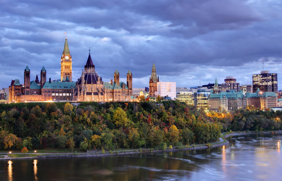 Ottawa's Parliament Hill beside a river at dusk with clouds in the sky