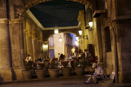 An artist who offers his paintings for sale sits next to a restaurant frequented by tourists in Havana March 16, 2016. REUTERS/Ueslei Marcelino