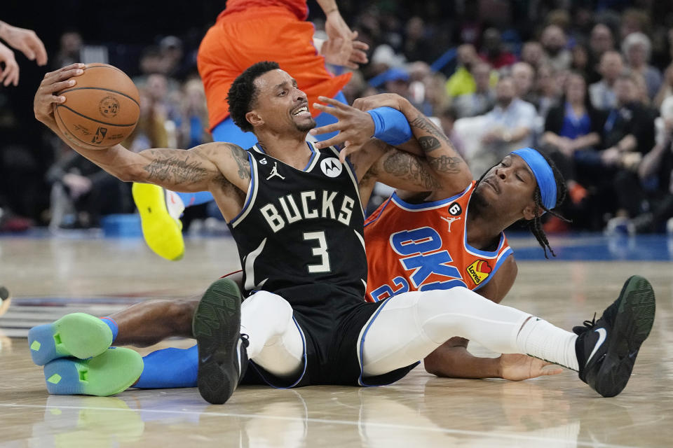Oklahoma City Thunder's Shai Gilgeous-Alexander, right, reaches for the ball held by Milwaukee Bucks' George Hill (3) during the first half of an NBA basketball game Wednesday, Nov. 9, 2022, in Oklahoma City. (AP Photo/Sue Ogrocki)
