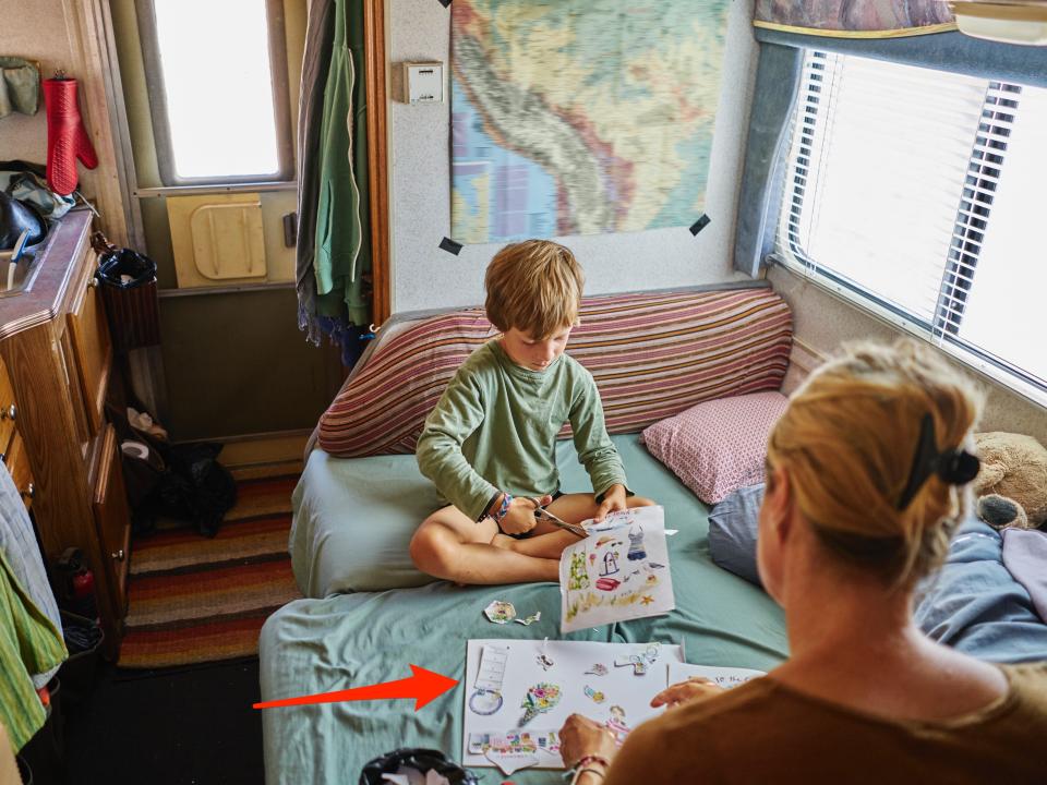 This image shows a mother and son cutting out pictures in camper van and an arrow pointing to a picture in the mom's hand