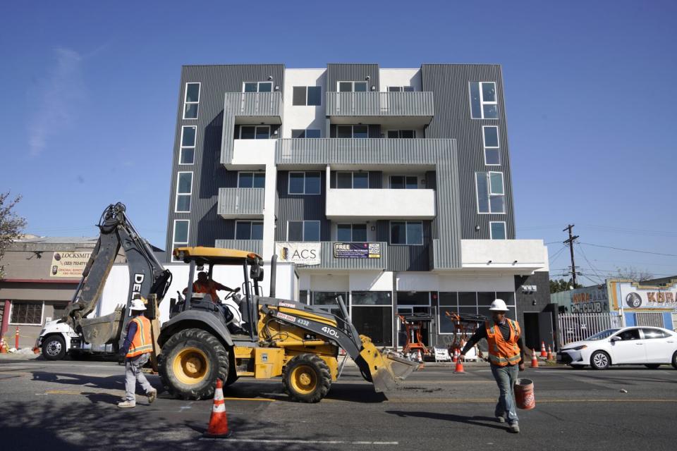 Construction workers and equipment outside a building