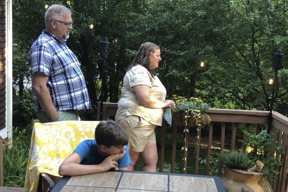 Homeowners Jean Andre, left, and Jen DeBedout, standing, with neighbor Ryland Leddy, seated, watch actors from the Vermont Shakespeare Festival, perform "Shakespeare," in their backyard, Thursday, June 25, 2020, in Burlington, Vt. The idea for the program known as "Shakespeare to You," or "Bard to Your Yard," was conceived as a way to keep live theater alive at a time when many social activities are being postponed or canceled amid the coronavirus pandemic. Actors with the festival have done more than 30 performances, live, online and by telephone. (AP Photo/Wilson Ring)