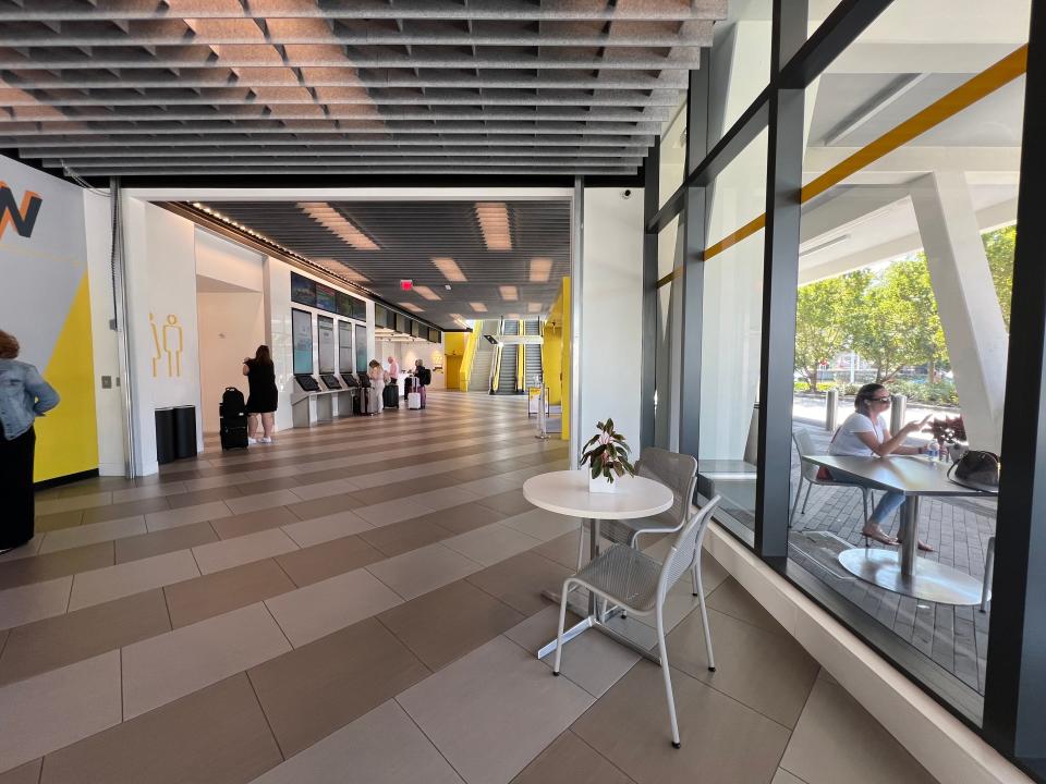 The lobby of a Florida Brightline station is shown. It is mostly an open space with muted gray tones and a few pops of yellow.
