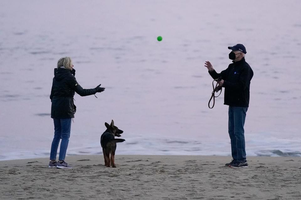 First lady Jill Biden tosses a ball to President Joe Biden as they take their dog Commander for a walk in Rehoboth Beach, Del., Tuesday, Dec. 28, 2021. 