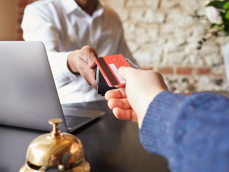 person handing a red credit card to the worker behind the desk at a hotel